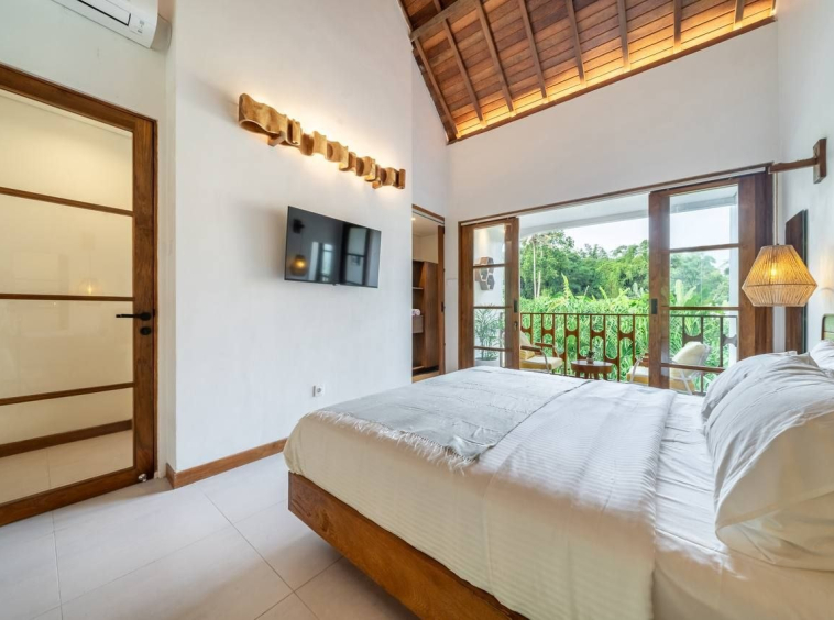 Bedroom with exposed beams, full-height doors to the balcony and a view of the greenery