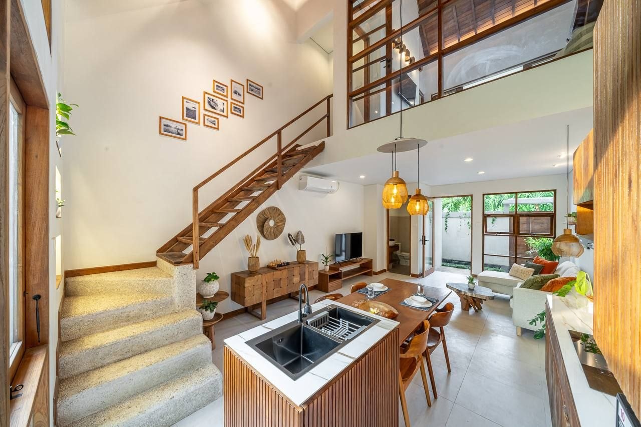 Open-plan kitchen and living room with an island and a staircase under a double-height ceiling