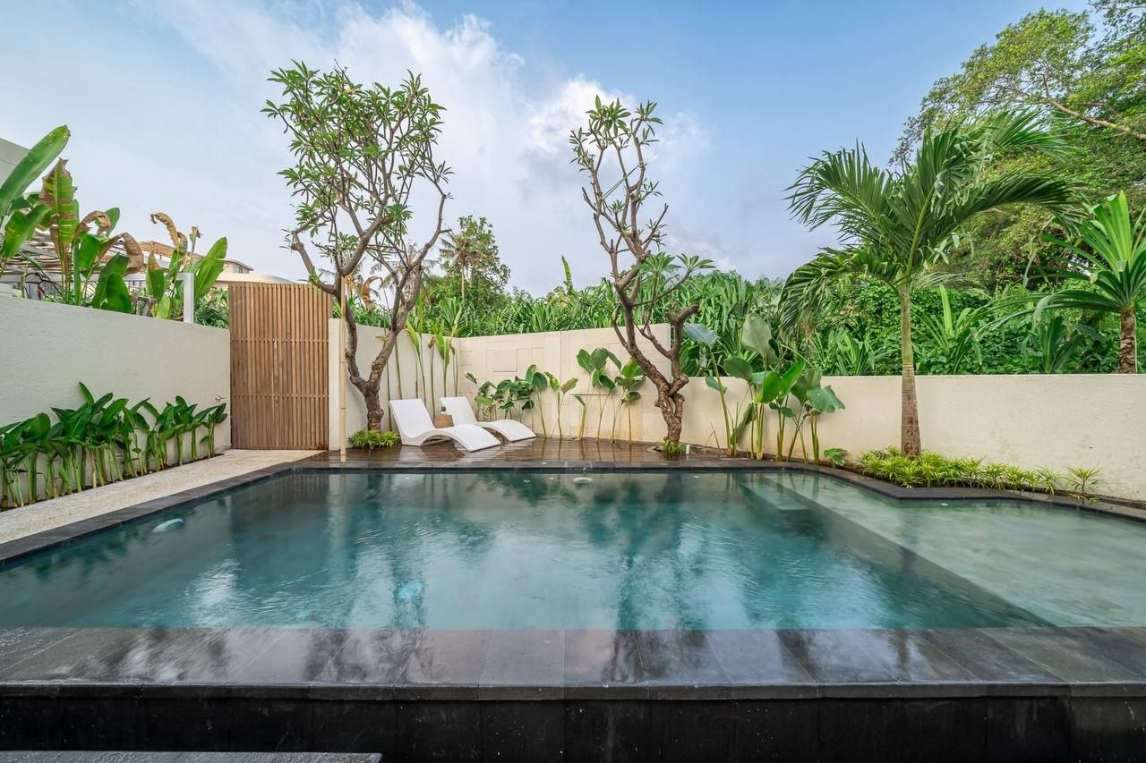 Pool with sun loungers, frangipani trees and tropical planting on the grounds